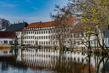 Fototapeta na wymiar Historical buildings at Brede in Lyngby, Denmark, reflecting in the almost still water.