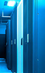 Row of closed racks clusters with servers and routers in big data centre with neon blue toning. Powerful internet, telecommunication equipment. Server room inside