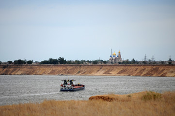 Fototapeta premium The ship sails on the river. On the shore stands the Orthodox Church