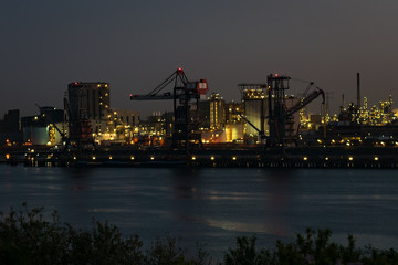 Cranes and lights in the harbor of Rotterdam, The Netherlands. The Europoort area is very heavily industrialised with petrochemical refineries and storage tanks, bulk iron ore and coal handling.