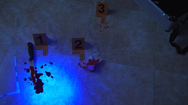 Police expert examines with flashlight UV traces of evidence at the scene of a crime, conceptual image