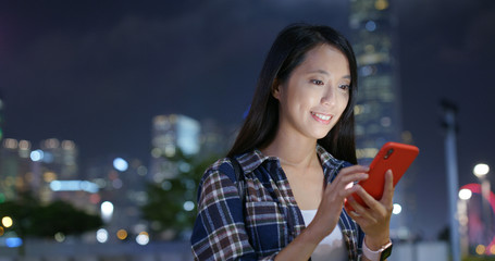 Woman use mobile phone online in the city at night