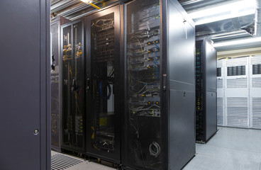 Network server room with parallel rows of mainframe. Corridor in big working data center full of rack servers and supercomputers.