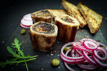 close up of rustic english bone marrow, pickled onion and toast