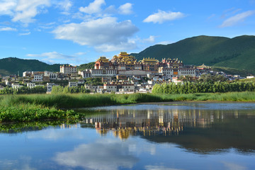 Fototapeta na wymiar Beautiful view of the Ganden Sumtseling Temple reflecting in the water. Zhongdian (Shangri-La), China