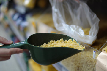 A female hand pours pasta in a bag.