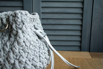 Extreme close-up of a handmade knitted bag in detail. Gray bag with leather bottom and straps.