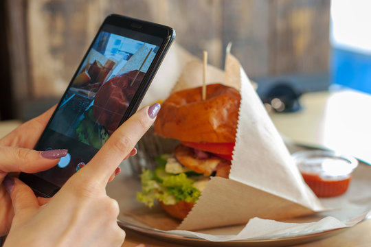girl takes a picture of tasty burger set. social media concept.