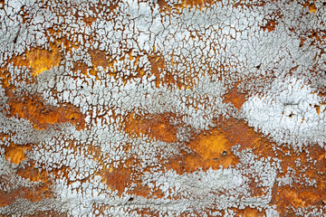Gray old battered wall with orange-yellow spots, deep dents and spots. Rough and harsh surface texture