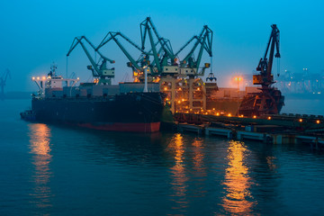 Fototapeta premium Cargo ship in port of Rizhao, China, inner harbor under deep blue twilight sky