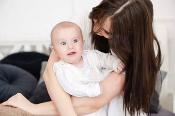 Fototapeta na wymiar Charming infant girl in mother arms indoors.