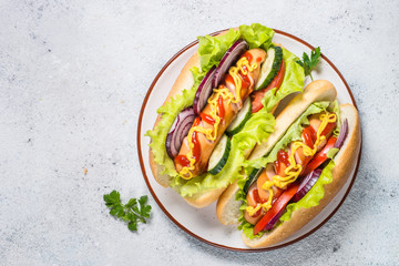 Hot dog with fresh vegetables on white top view.