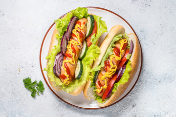 Hot dog with fresh vegetables on white top view.