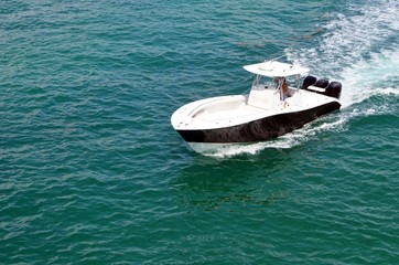 Fototapeta premium Small black with white trim fishing boat weed by three outboard engines cruising on the Florida Intra-Coastal Waterway near the MacArthur Causeway in Miami Beach,Florida