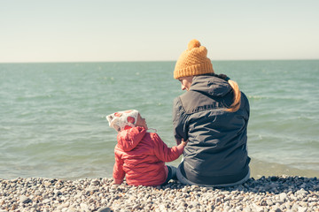 Mother and daughter are sitting on the beach