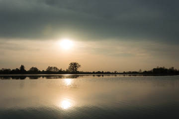 Sun behind a foggy sky over a calm lake