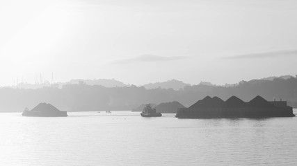 beautiful view of traffic of tugboats pulling barge of coal at Mahakam River, Samarinda, Indonesia at dawn. Mining and cargo industry background