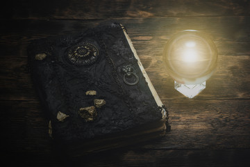 Crystal ball and a magic book on a wizard table background.