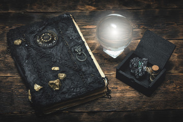 Crystal ball and a magic book on a wizard table background.