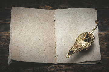 A Wish list mock up, quill pen and a golden magic lamp on a wooden board background. Fulfillment of...
