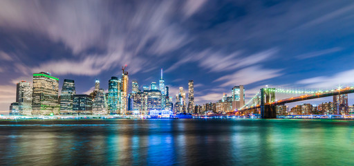 Naklejka na ściany i meble Manhattan panoramic skyline at night with Brooklyn Bridge. New York City, USA. Office buildings and skyscrapers at Lower Manhattan (Downtown Manhattan)..