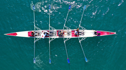 Aerial drone bird's eye view photo of red sport canoe operated by team of young men and women in...