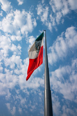 Mexican flag fluttering over a cloud sky.