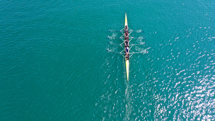 Aerial drone bird's eye view photo of yellow sport canoe operated by team of young team in emerald...