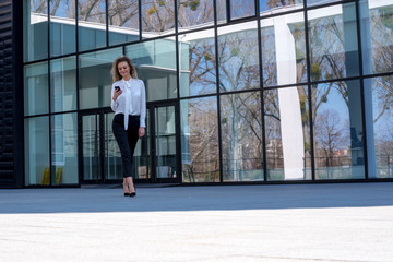 Fototapeta na wymiar Young successful business woman walking outdoor in front of an office building