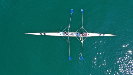 Aerial drone bird's eye view of sport canoe operated by 2 young women in turquoise clear waters