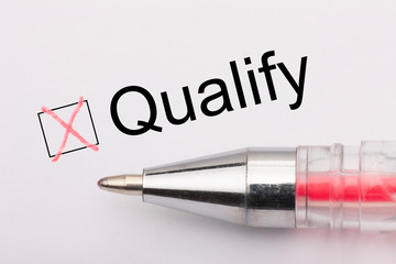 Qualify - checkbox with a cross on white paper with pen. Checklist concept.