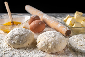 White flour with eggs, butter and dough on a cooking board