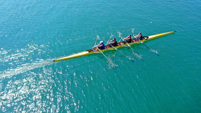 Aerial drone bird's eye view photo of yellow sport canoe operated by team of young team in emerald clear sea © aerial-drone