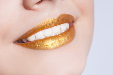 Beautiful closeup female lips with gold color makeup