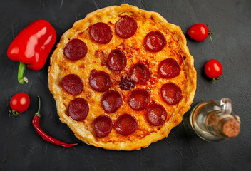 Tasty pepperoni pizza of tomatoes and ingredients on concrete background.