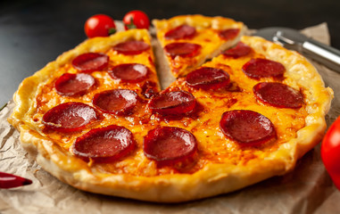 Tasty pepperoni pizza of tomatoes and ingredients on concrete background.