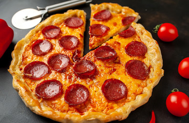 Tasty pepperoni pizza of tomatoes and ingredients on concrete background.