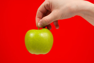 Hand holding tasty organic green delicious apple Isolated on red Background