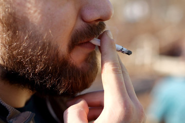 Portrait of brutal adult working  man after labor day  with a beard close up smoking  cigarette,...