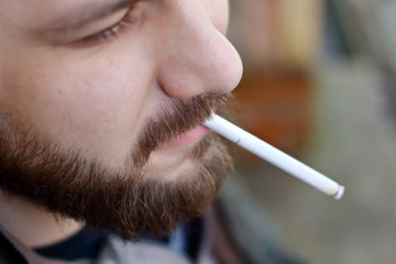 Portrait of brutal adult working  man after labor day  with a beard close up smoking  cigarette,...