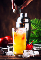 Summer tequila sunrise cocktail with silver tequila, grenadine syrup, orange and ice cubes. Wooden...