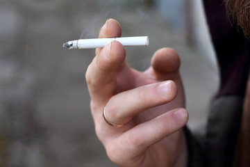Cigarette in the brutal male man hand with wedding ring. Smoking is a bad habit