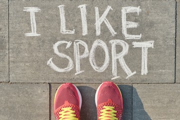 Text i like sport written on gray pavement with woman legs in sneakers, view from above
