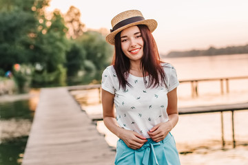 Obraz premium Beautiful young woman walking on pier at sunset in summer.