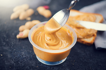 Peanut butter. Creamy smooth peanut butter in a jar on a table. Spoon of Natural nutrition. Organic food
