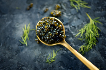 Black caviar in a spoon on dark background. Natural sturgeon black caviar closeup. Delicatessen. Top view, flatlay
