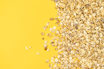 Dry rolled oatmeal on yellow background - isolated