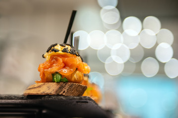Delicious appetizer with salmon. Closeup with bokeh and glowing lights. Good catering service on event.