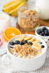 Bowl of granola with milk and berries. Healthy breakfast cereal food on white table