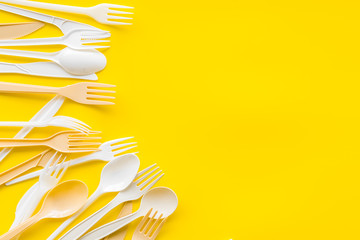 Plastic utilization concept with flatware on yellow background top view mock up
